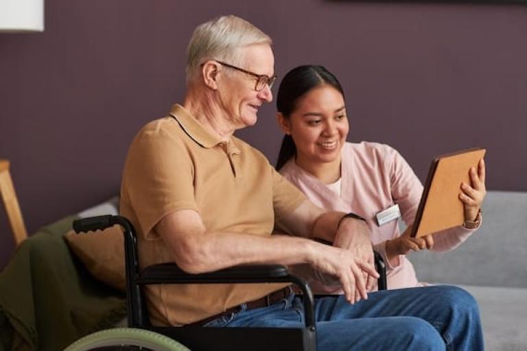 Woman using tablet computer with elderly man